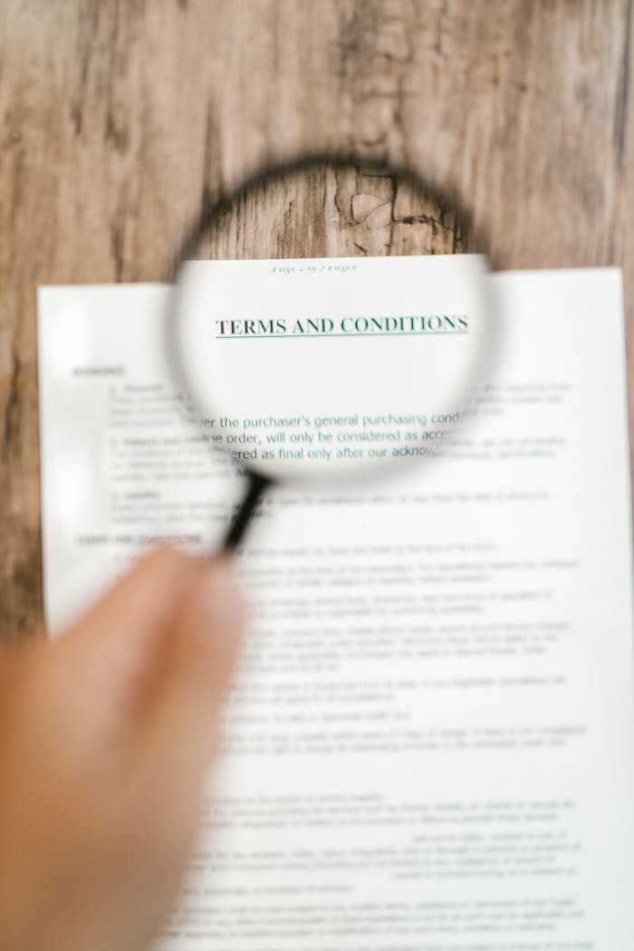 Magnifying glass focusing on 'Terms and Conditions' in a document. Ideal for business and legal themes.