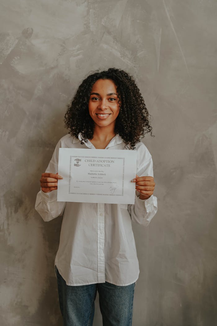 A joyful woman proudly displays an adoption certificate.